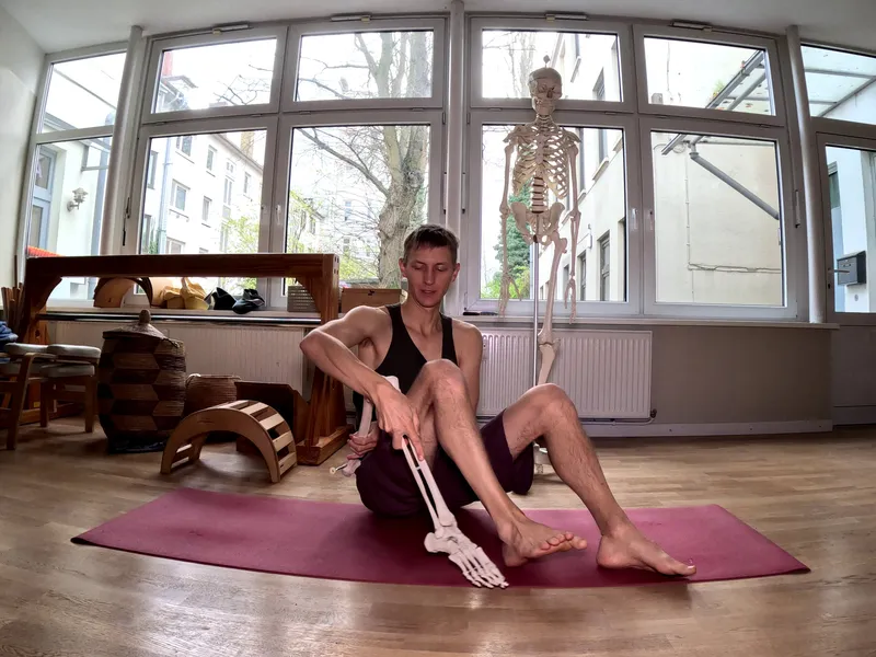A person on a yoga mat holding an artificial leg next to his own leg.