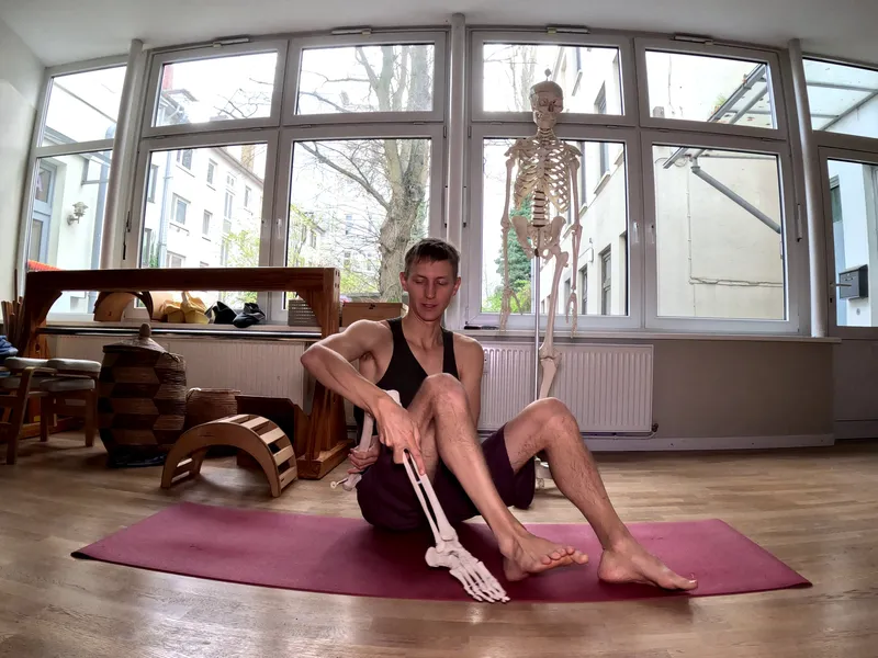 A person on a yoga mat holding an artificial leg next to his own leg.