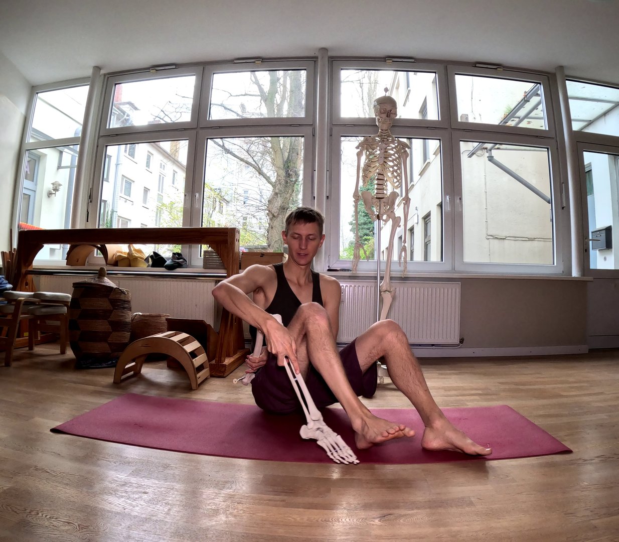 A person on a yoga mat holding an artificial leg next to his own leg.